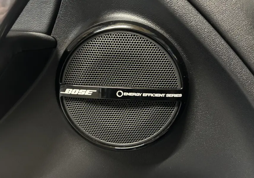Gros plan sur l'enceinte Bose noire intégrée à l'intérieur de la Renault Mégane Coupé 2.0 DCI 165 GT blanche.