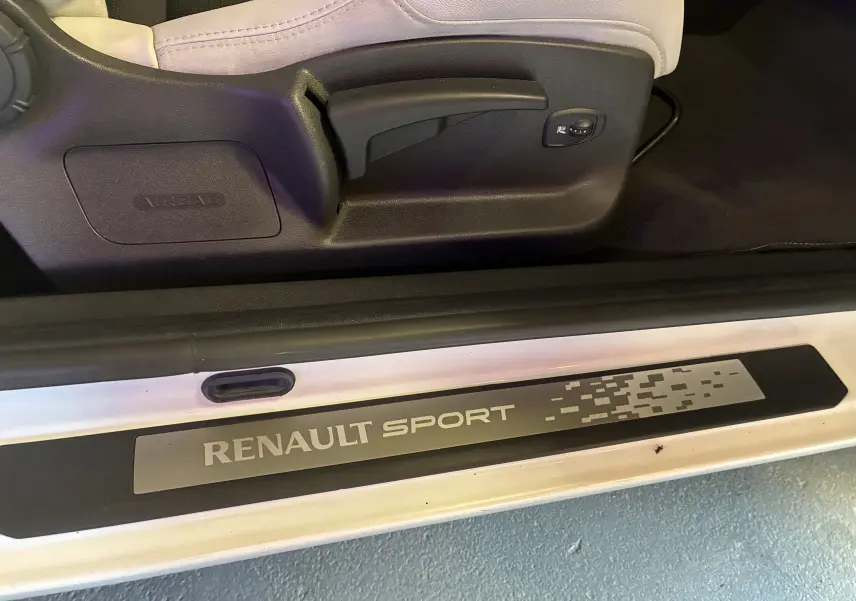 Détail de la marche intérieure blanche avec logo Renault Sport et réglage siège côté conducteur d’une Renault Mégane Coupé.