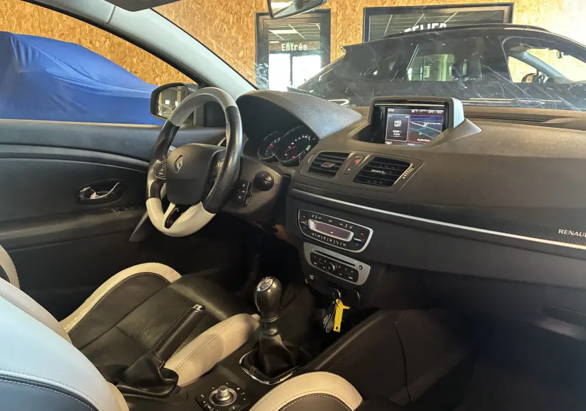 Vue intérieure côté conducteur de la Renault Mégane Coupé 2.0 DCI 165 GT 2014, volant cuir bicolore et écran tactile 7 pouces.