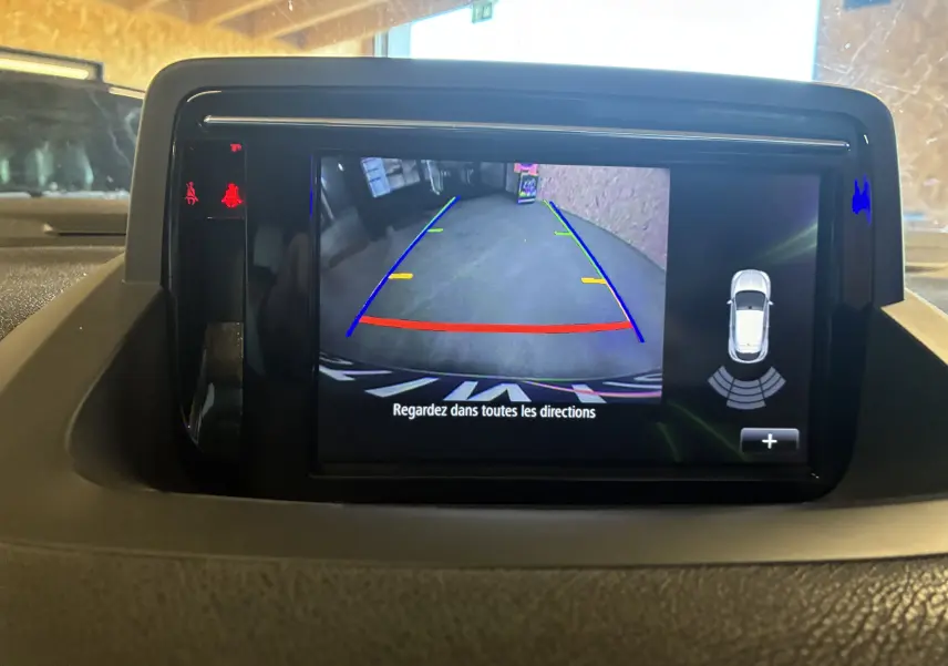 Écran tactile intérieur de Renault Mégane Coupé blanc 2014 montrant la caméra de recul avec aides au stationnement.