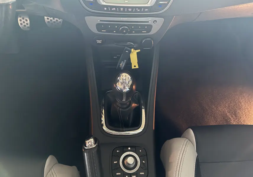 Vue plongeante sur la console centrale noire de la Renault Mégane Coupé 2.0 DCI 165 GT avec levier de vitesse manuel et commandes multimédia.