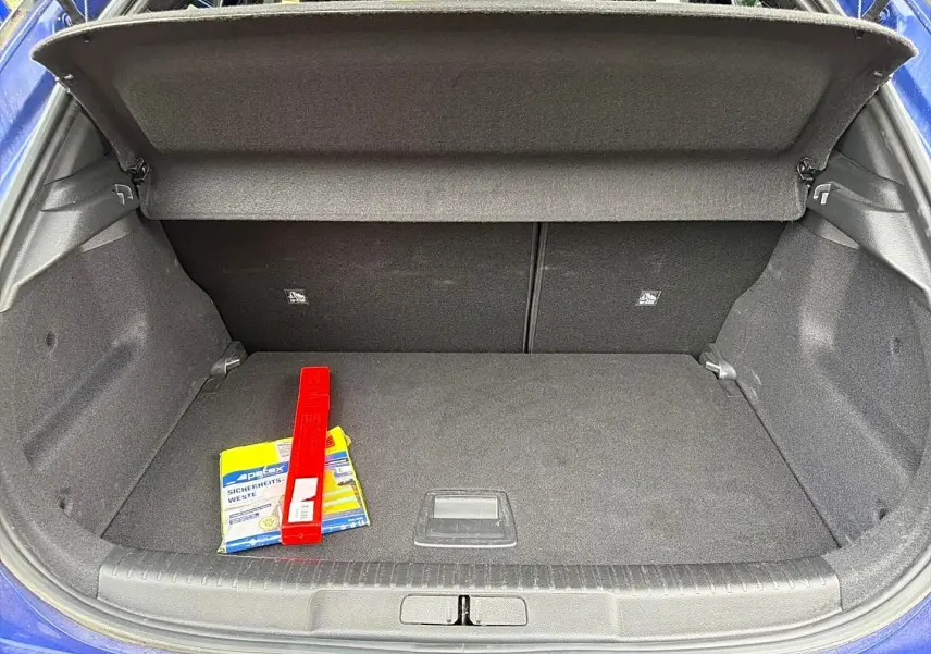 Vue du coffre ouvert d’un Opel Mokka bleu 2025, montrant un espace de rangement avec un triangle de signalisation et un gilet de sécurité.