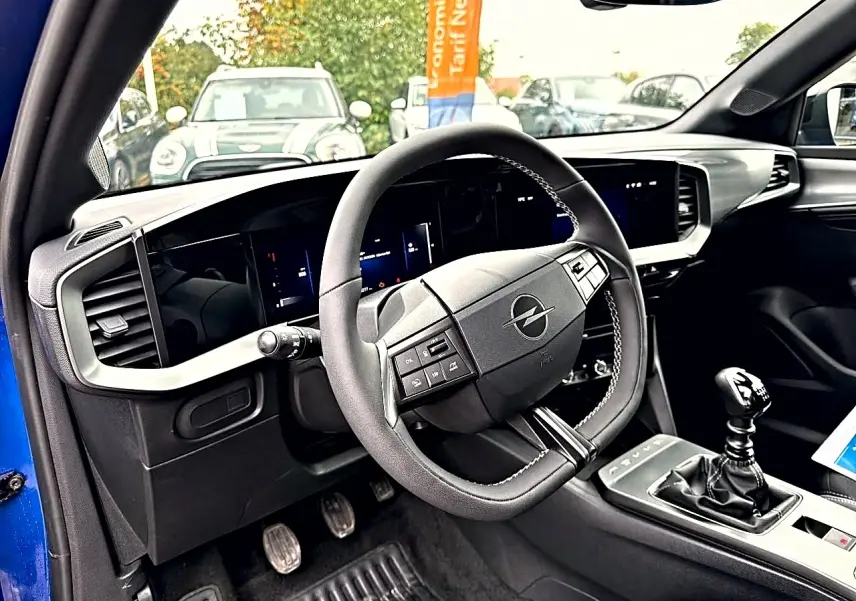 Vue intérieure côté conducteur de l’Opel Mokka bleu 2025, volant multifonction et levier de vitesse manuel visibles.