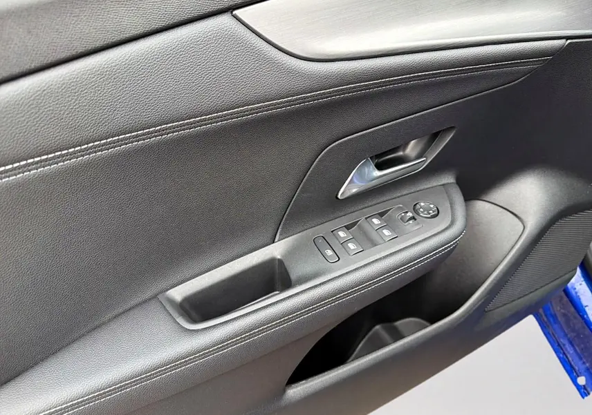Détail de la porte avant gauche noire de l’Opel Mokka 1.2 turbo 136 édition avec commandes de vitres et poignée chromée.
