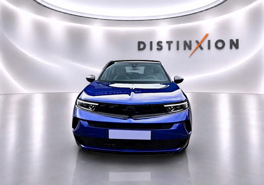 Vue frontale d'un Opel Mokka 1.2 turbo 136 edition bleu, avec calandre noire et phares LED fins dans un showroom lumineux.