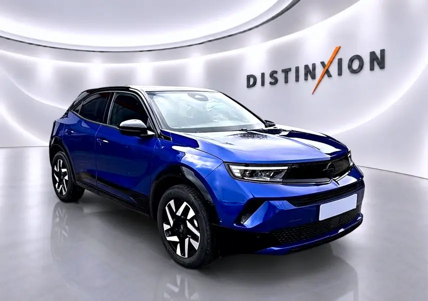 Opel Mokka 1.2 turbo bleu en 3/4 avant droit, avec jantes noires et blanches, dans un showroom lumineux.