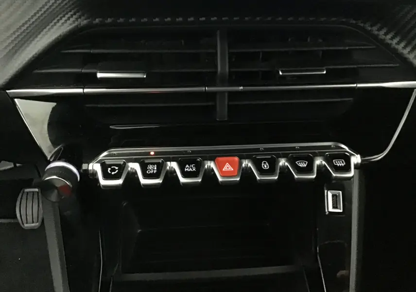 Tableau de bord de Peugeot 208 gris Artense 2022, vue centrée sur les commandes en forme de touches piano chromées.