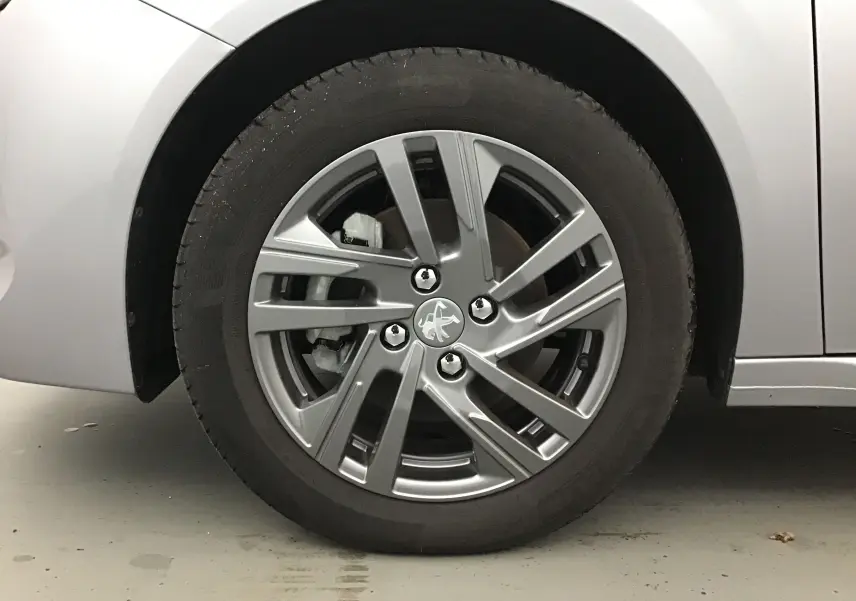 Gros plan sur la roue avant gauche de la Peugeot 208 gris Artense, mettant en valeur la jante alliage 16 pouces au design moderne.