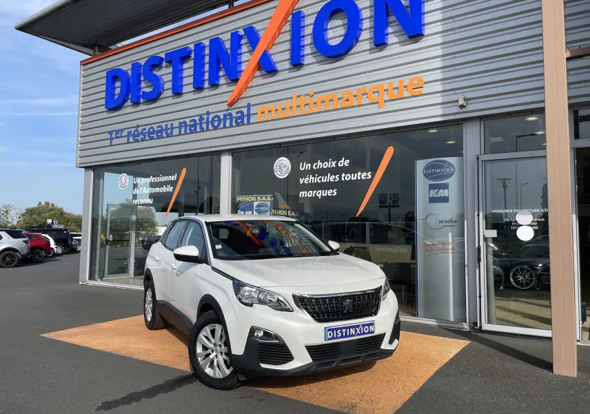 Peugeot 3008 blanc en 3/4 avant droit devant un showroom Distinxion avec calandre noire et jantes argentées.