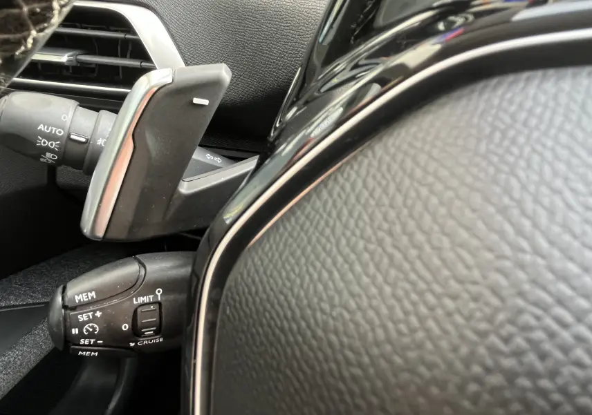Détail du volant et des commandes de régulateur de vitesse du Peugeot 3008 1.5 BlueHDi blanc, intérieur noir.