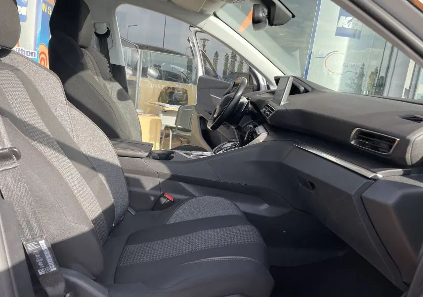 Intérieur côté conducteur du Peugeot 3008 blanc 2018, sièges gris-noir et tableau de bord moderne avec écran tactile.