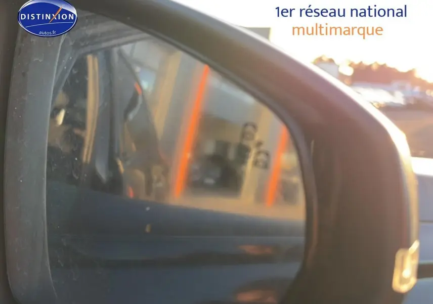 Rétroviseur extérieur droit noir du DS7 1.5 BlueHDi 130 Performance Line avec reflet flou d’un bâtiment au coucher du soleil.