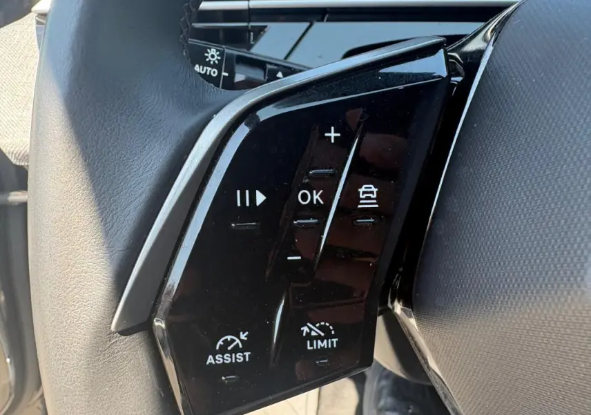 Gros plan sur les commandes au volant du Peugeot 3008 Hybrid 145 e-DCS6 Allure gris, montrant les boutons d'assistance et limiteur de vitesse.