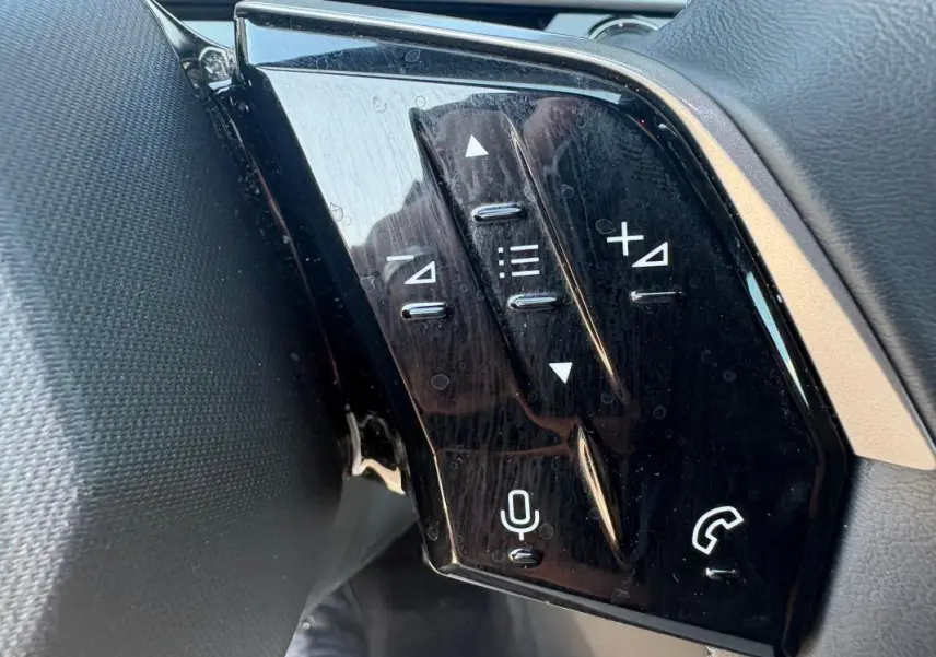 Gros plan sur les commandes au volant noir brillant du Peugeot 3008 Hybrid 145 e-DCS6 Allure gris, côté gauche.