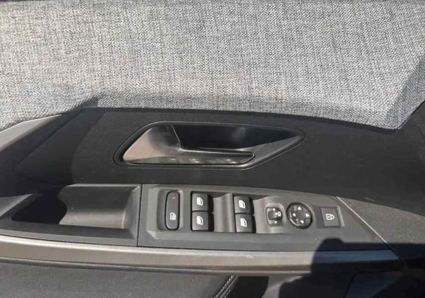 Vue rapprochée de la porte côté gauche du Peugeot 3008 gris, montrant les commandes des vitres et rétroviseurs.