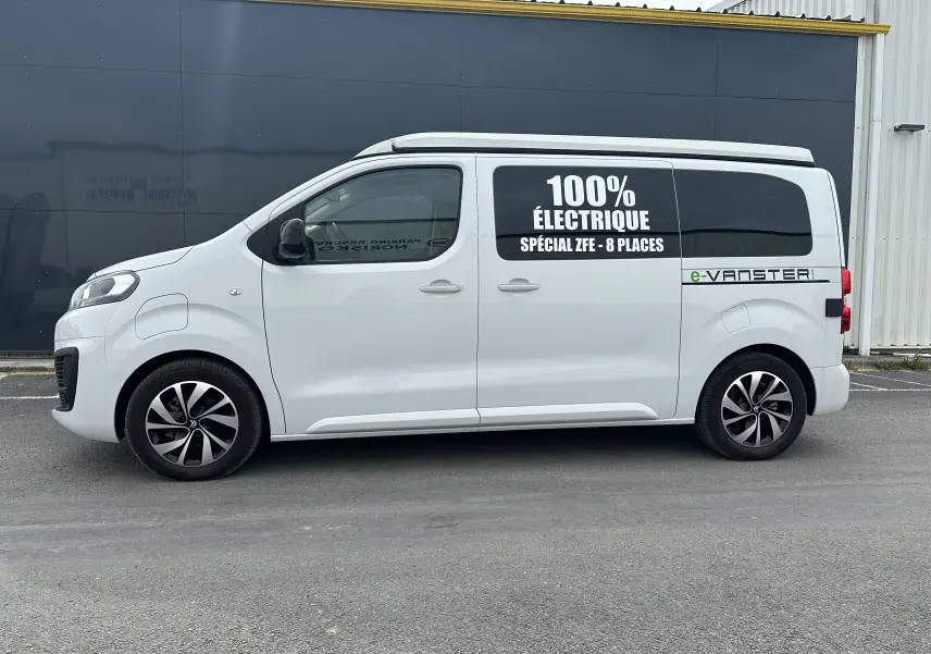 Profil côté gauche du Citroën Jumpy van blanc électrique avec toit relevable et inscriptions "100% électrique" sur la vitre arrière.