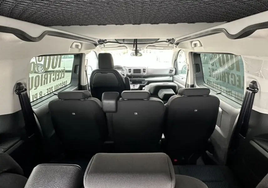 Vue intérieure arrière du Citroën Jumpy van blanc, montrant les sièges noirs et le tableau de bord à l'avant.