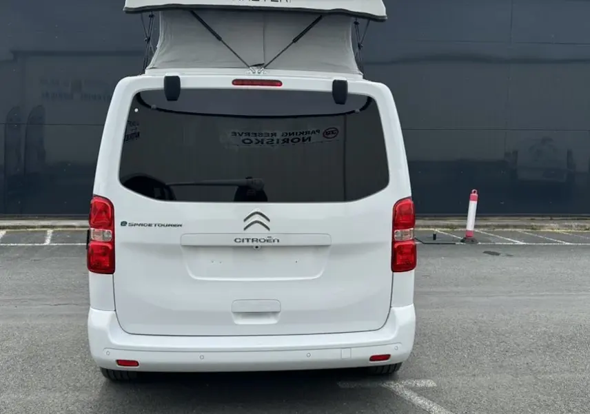 Vue arrière d'un Citroën Jumpy van blanc électrique avec toit relevable e-Vanster déployé sur parking.