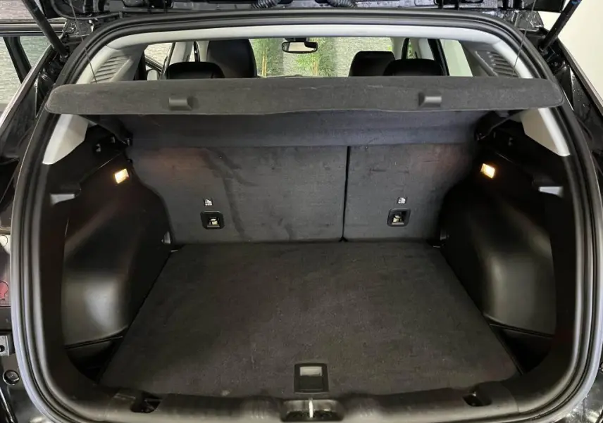 Coffre ouvert du Jeep Compass noir 2024, vue arrière montrant l'espace de chargement avec cache-bagages et éclairage intérieur.