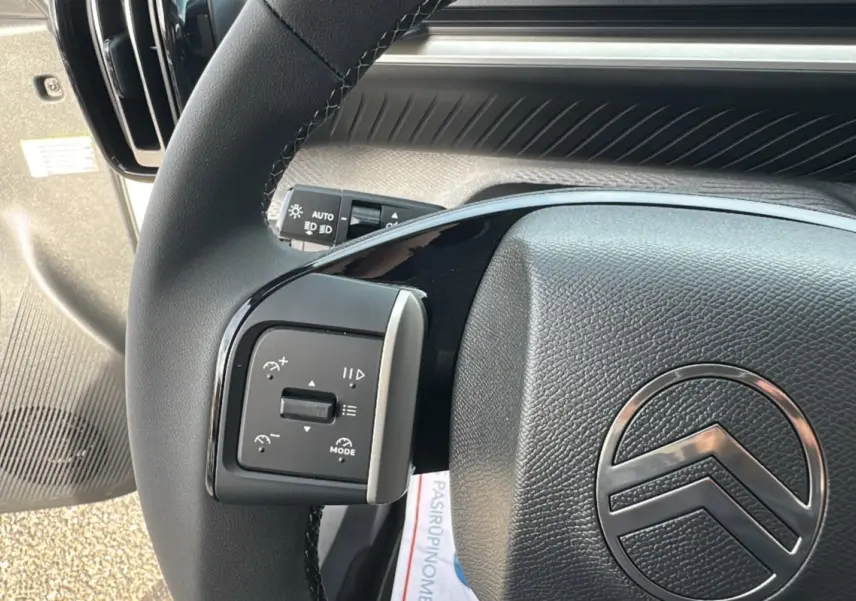 Gros plan sur le volant cuir noir de la Citroën C3 Aircross blanc banquise, avec commandes multifonctions visibles à gauche.