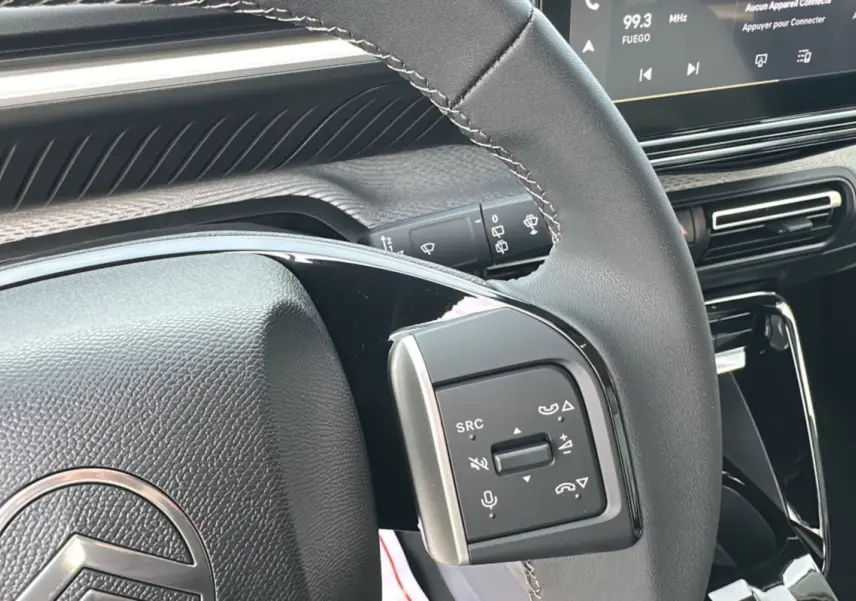Gros plan sur le volant cuir multifonctions de la Citroën C3 Aircross Hybrid 145 avec tableau de bord tactile en arrière-plan.