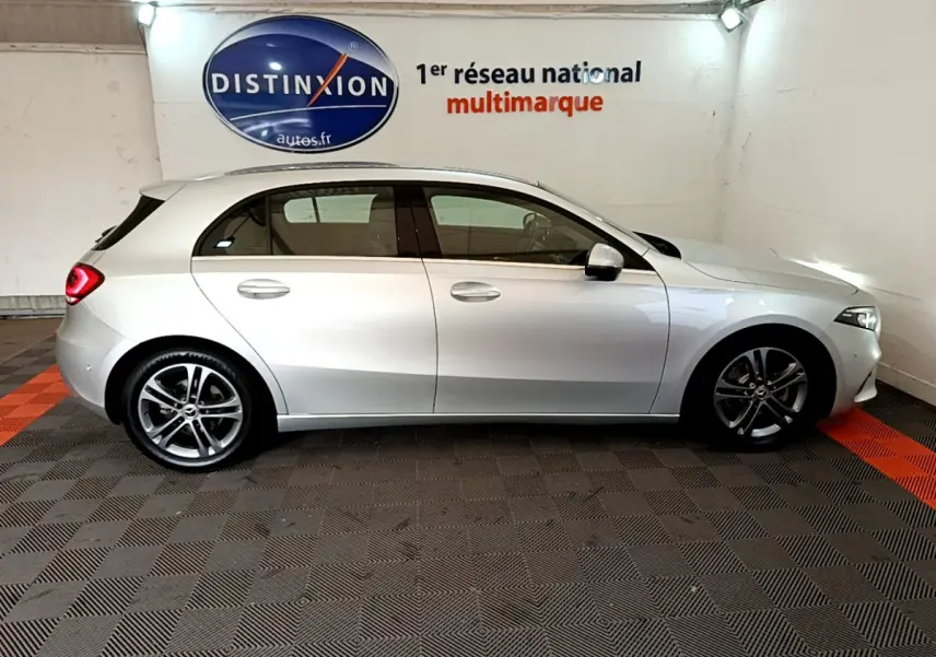 Profil côté droit d'une Mercedes Classe A gris clair 2020 garée en intérieur sur sol à damier noir et rouge.