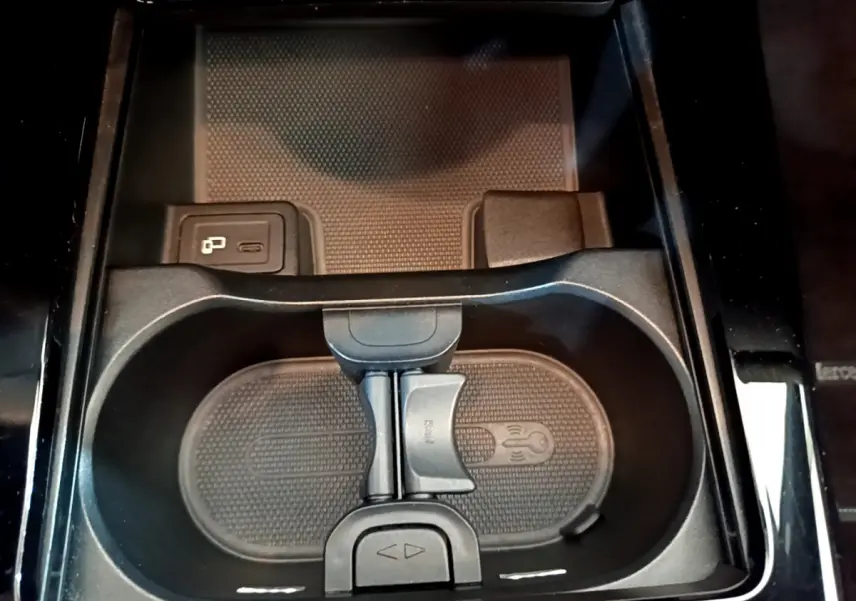 Gros plan sur le porte-gobelets central noir avec prise USB et finition brillante dans une Mercedes Classe A gris clair.