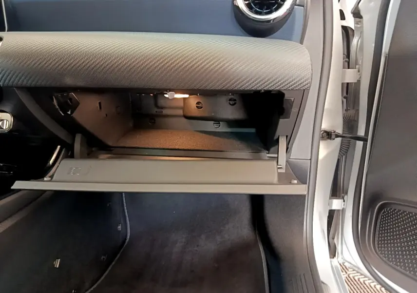 Vue intérieure côté passager de la boîte à gants ouverte du Mercedes Classe A gris clair 2020, avec éclairage intérieur.