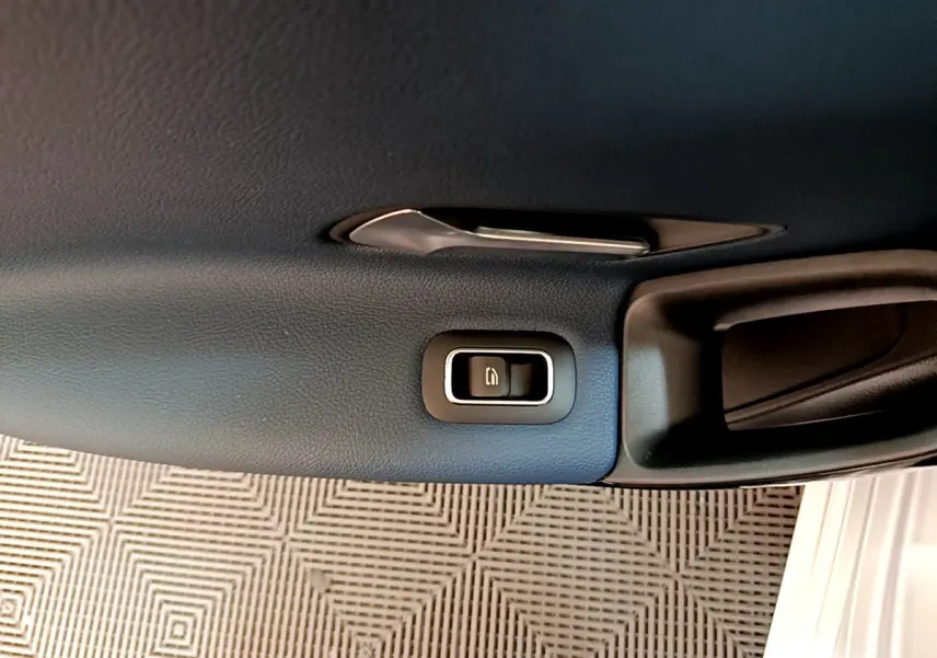 Bouton de verrouillage des portes sur la garniture intérieure noire de la porte côté droit d'une Mercedes Classe A gris clair.