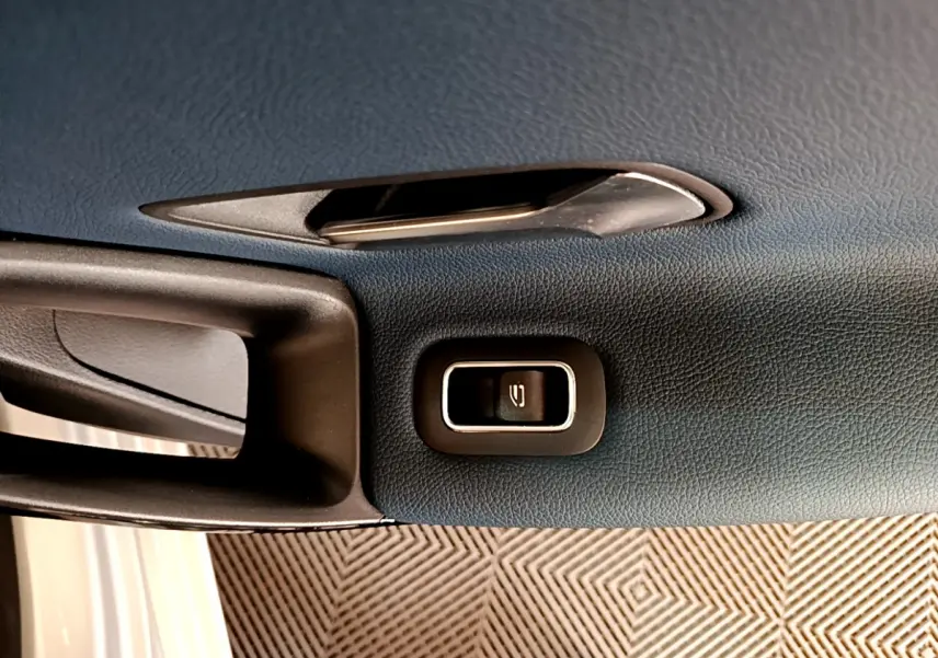 Gros plan sur la poignée intérieure et le bouton de verrouillage de porte d'une Mercedes Classe A gris clair.