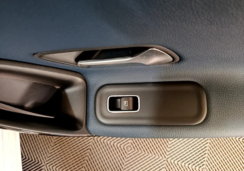 Gros plan sur la commande de lève-vitre côté conducteur dans l'habitacle gris foncé d'une Mercedes Classe A 180 d Business Line 2020.