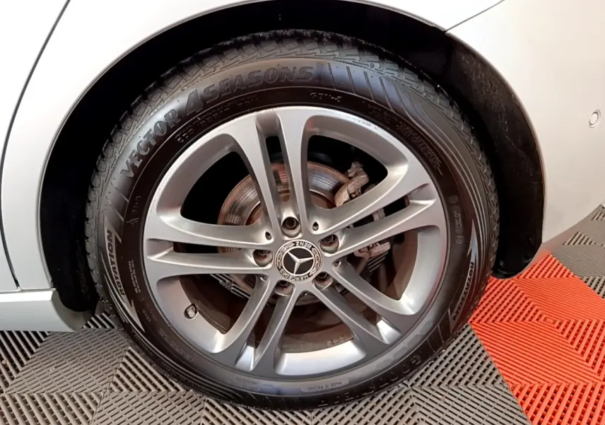 Gros plan sur la roue avant gauche gris clair d'une Mercedes Classe A 180 d Business Line 2020 avec jante alliage.