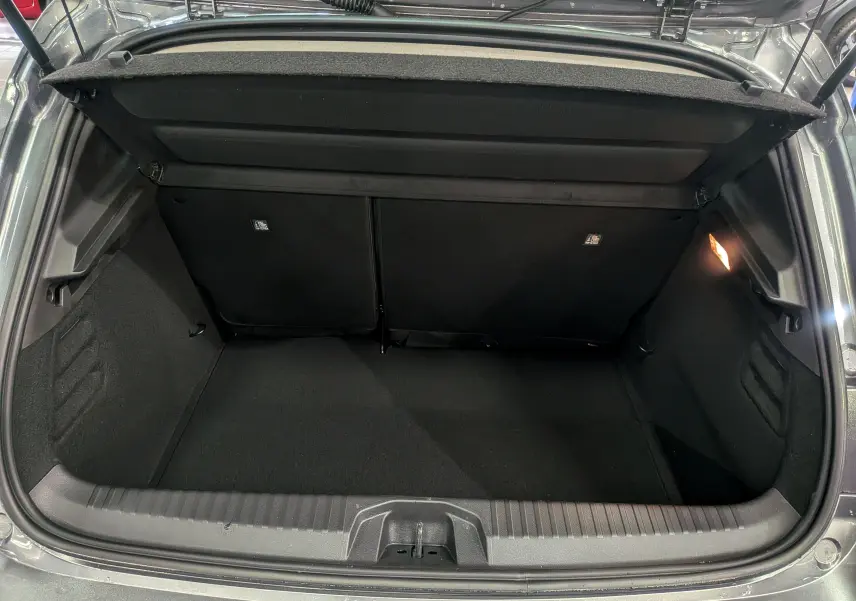 Coffre ouvert vu de l'arrière d'une Renault Clio V Gris Schiste 2025, montrant un espace de chargement propre et éclairé.
