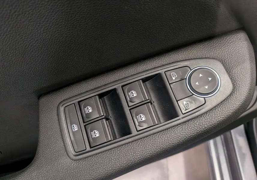 Gros plan sur les commandes électriques des vitres et rétroviseurs côté conducteur de la Renault Clio V gris schiste.
