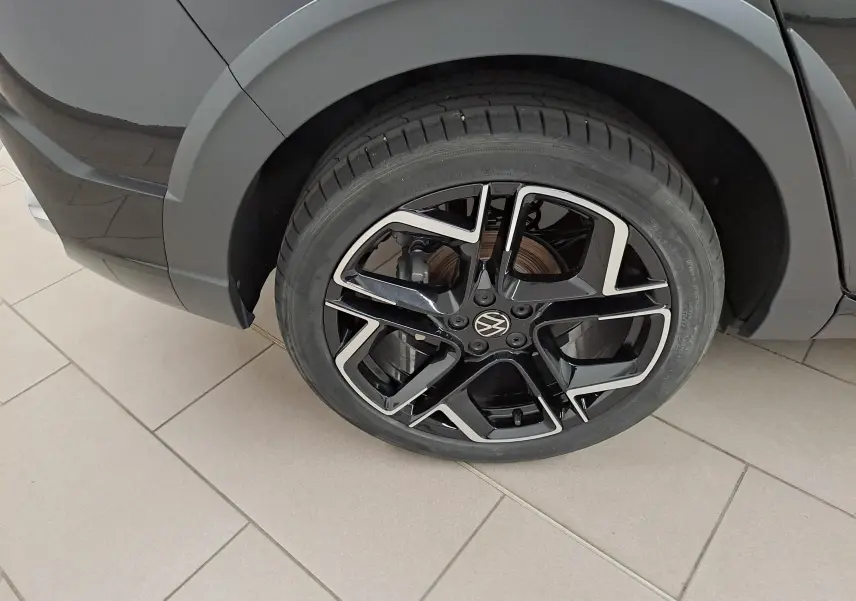 Gros plan sur la roue avant droite avec jante alliage noir et argent du Volkswagen Taigo Noir Intense nacré.