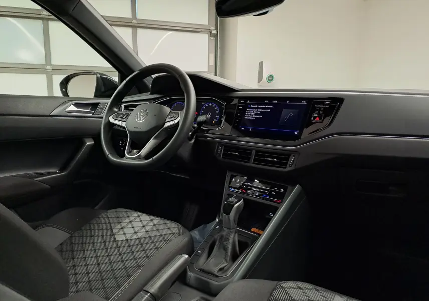 Vue intérieure côté conducteur du Volkswagen Taigo 2025, tableau de bord noir avec écran tactile et volant multifonctions.