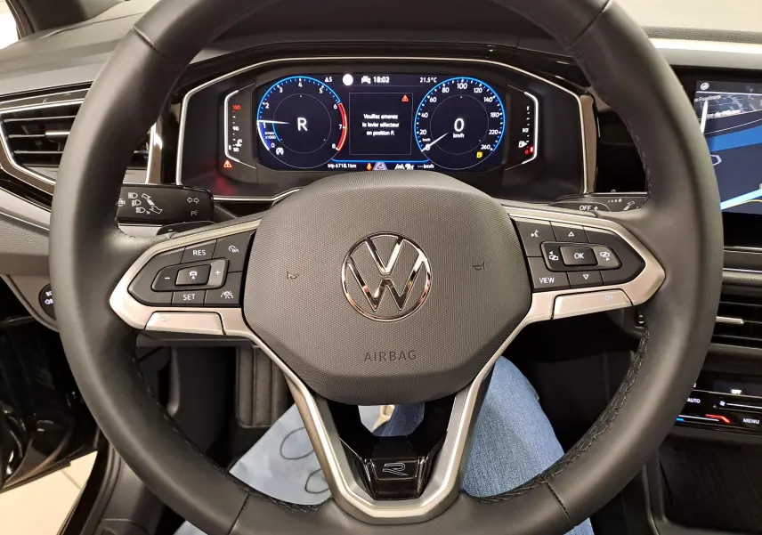 Vue rapprochée du volant cuir multifonctions avec logo Volkswagen et tableau de bord digital du Taigo noir intense nacré.