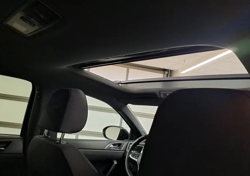 Vue intérieure du Volkswagen Taigo noir intense nacré, mettant en valeur le toit ouvrant électrique et les sièges avant.