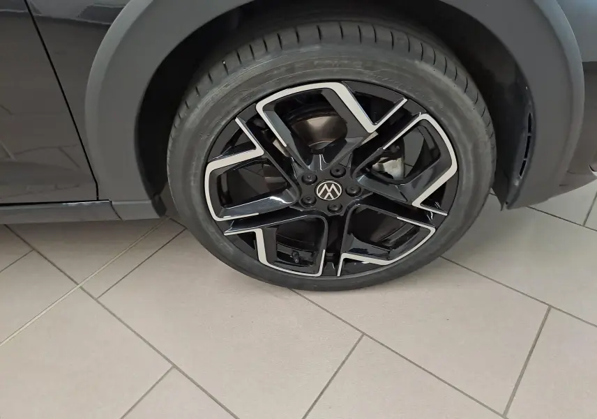 Gros plan sur la roue avant gauche avec jante alliage noir et argent du Volkswagen Taigo Noir Intense nacré.