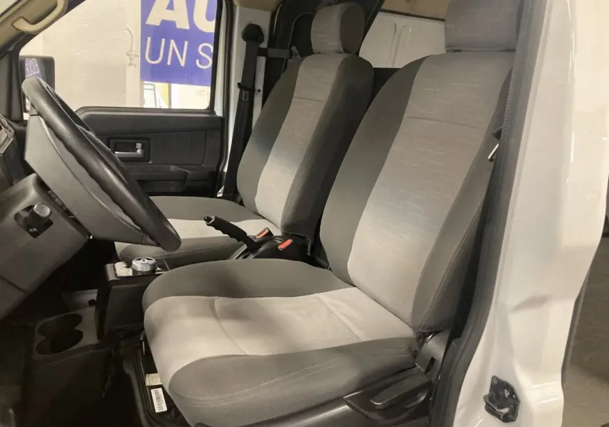 Vue intérieure côté conducteur du DFSK EC35 Ecocity 2022, montrant les sièges gris et la porte blanche ouverte.