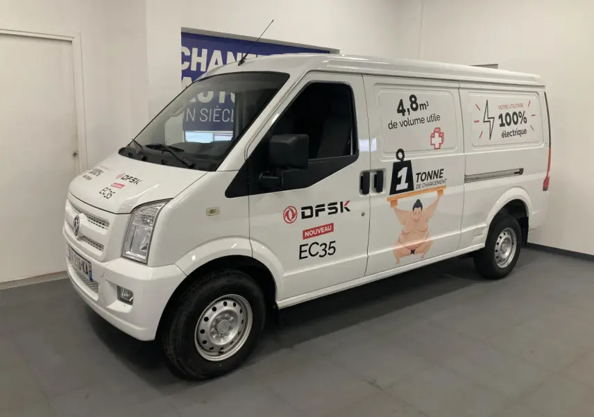 Vue 3/4 avant droit du fourgon blanc DFSK EC35 Ecocity électrique avec marquages publicitaires sur la carrosserie.