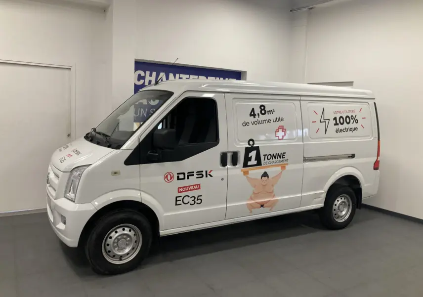 Vue de profil côté gauche d’un utilitaire blanc DFSK EC35 Ecocity 2022 avec marquages publicitaires électriques sur la carrosserie.