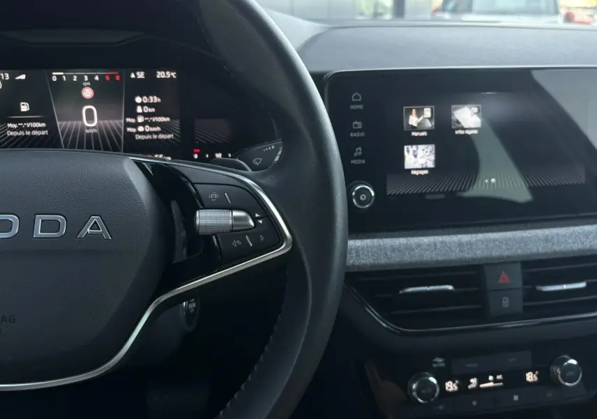 Intérieur SKODA SCALA TSI 116 DSG7, vue du volant cuir à deux branches et écran tactile central allumé.