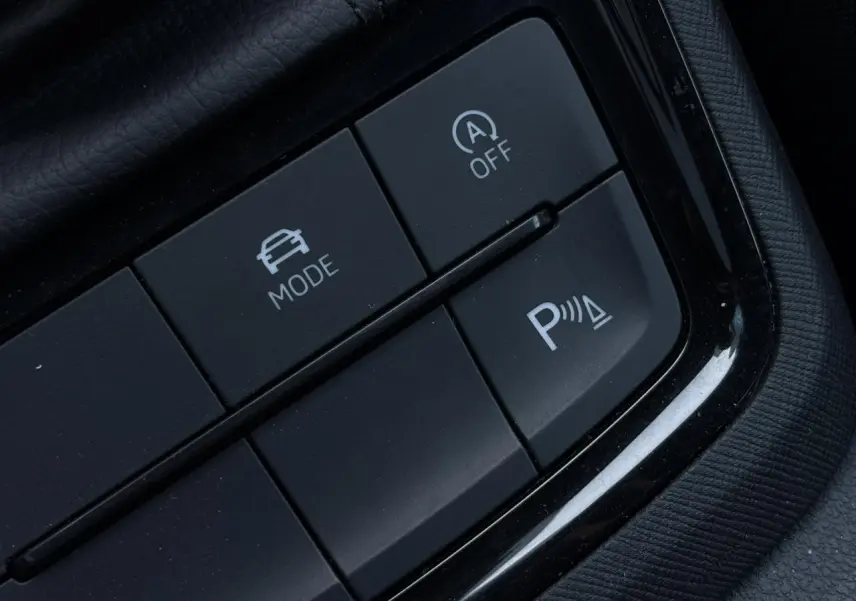 Gros plan sur les boutons de commande du mode de conduite et du stationnement assisté dans une Skoda Scala gris reflex.