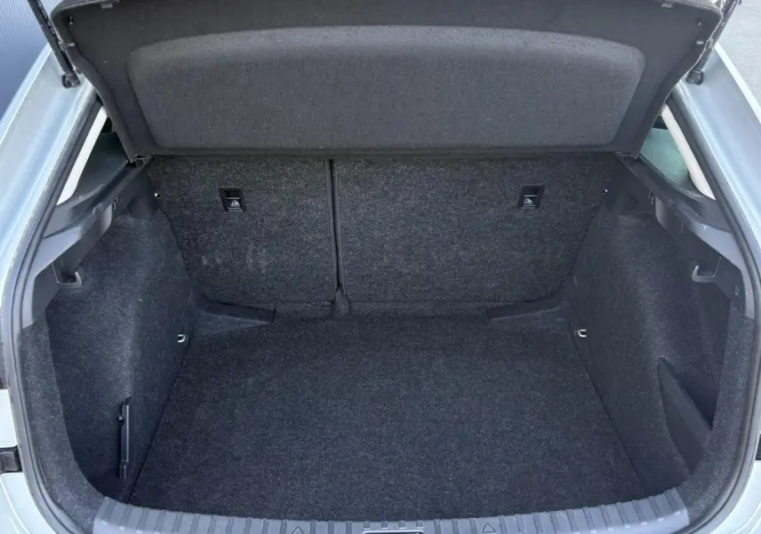 Coffre ouvert d'une Skoda Scala TSI 116 DSG7 gris Reflex, vue arrière montrant l'espace de chargement vide et tapissé.