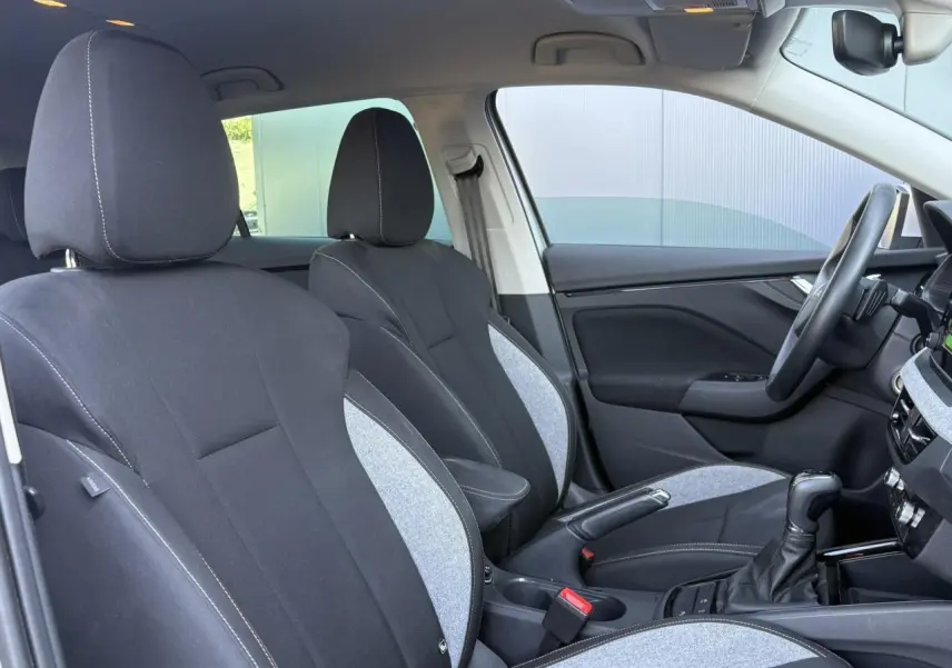 Vue intérieure côté droit de la Skoda Scala 2025, sièges tissu noir et gris avec surpiqûres blanches et console centrale.