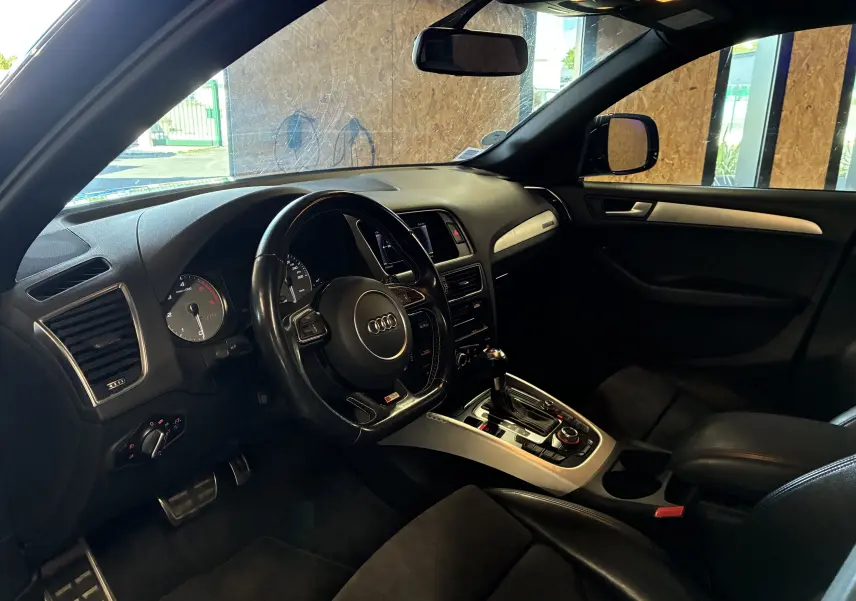Vue intérieure côté conducteur de l'Audi SQ5 noir, avec volant cuir multifonctions et console centrale argentée.