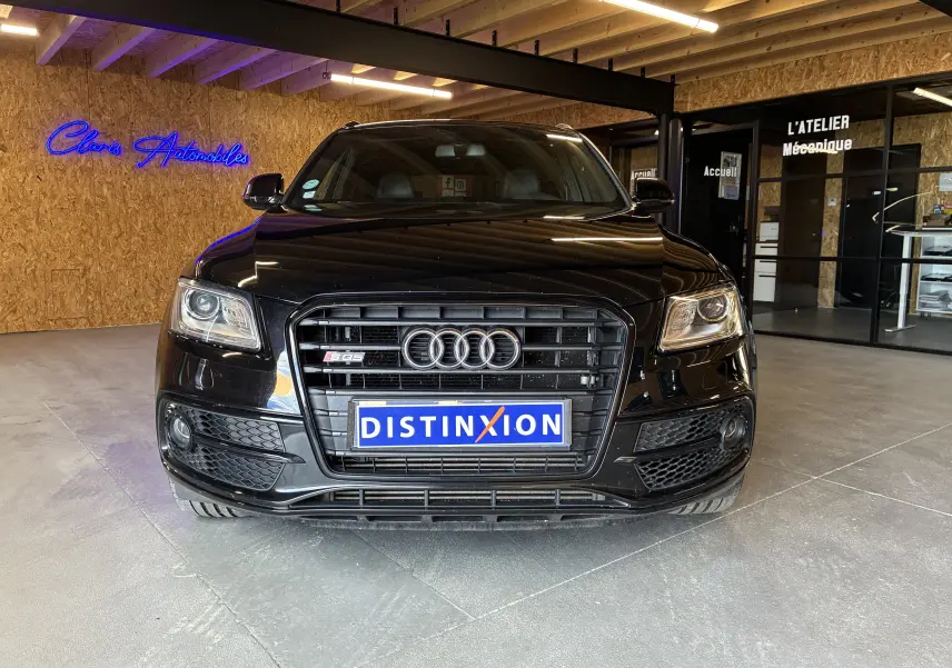 Audi SQ5 noir vue de face, mettant en valeur la calandre distinctive et les phares xénon allumés.