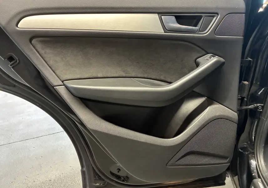 Porte arrière gauche ouverte de l'Audi SQ5 noire, avec garniture noire et insert métal brossé, haut-parleur intégré.