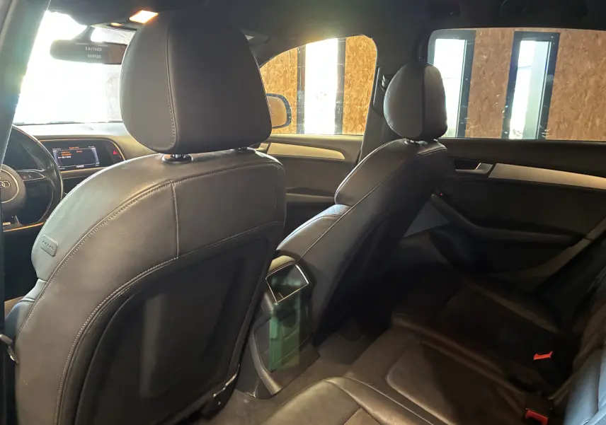Vue intérieure arrière de l'Audi SQ5 noir, montrant les sièges en cuir et la console centrale entre les sièges avant.